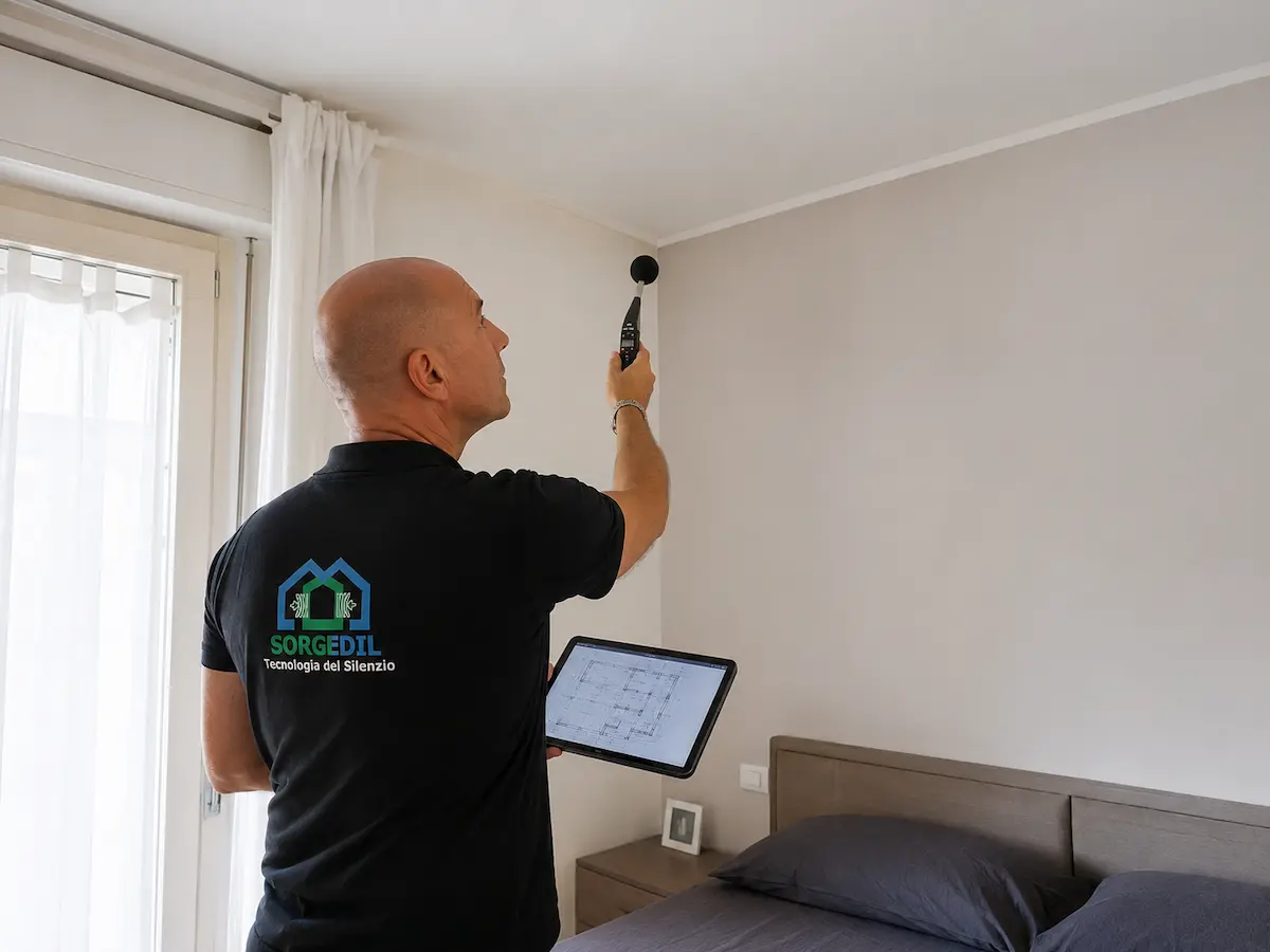 Tecnico Sorgedil analizza il raccordo tra parete e soffitto di una stanza residenziale utilizzando un tablet