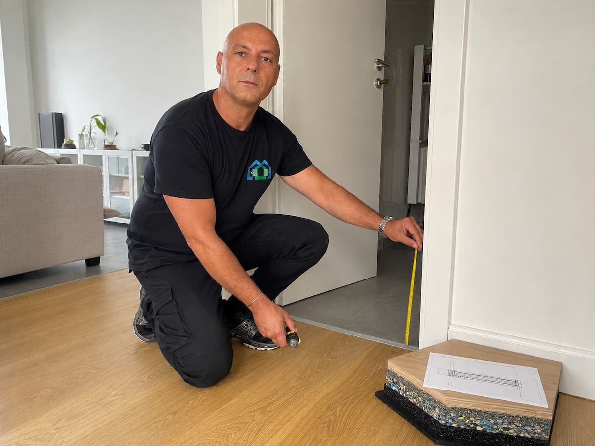 Tecnico Sorgedil mentre verifica il pavimento esistente, la soglia e la quota inferiore di una porta prima del progetto acustico